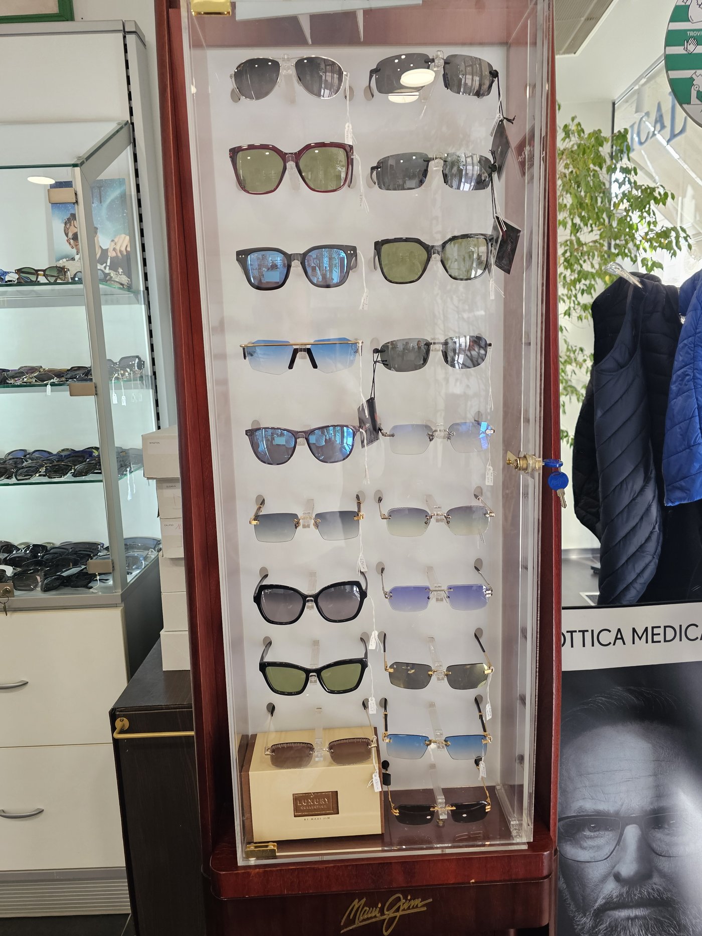 Vetrina Maui Jim in plexiglass e legno con occhiali da sole a lenti specchiate, verdi e sfumate da Ottica Medical